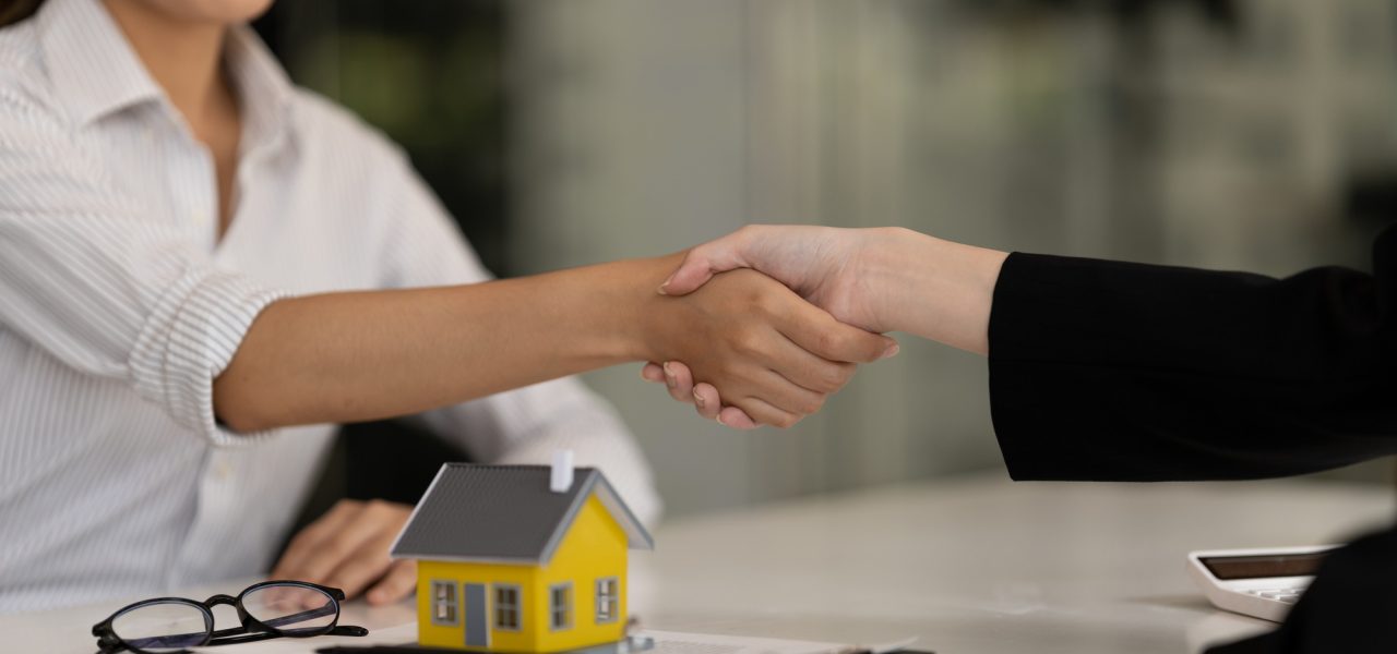 Real estate broker and customer shaking hands after signing a contract: real estate, home loan and